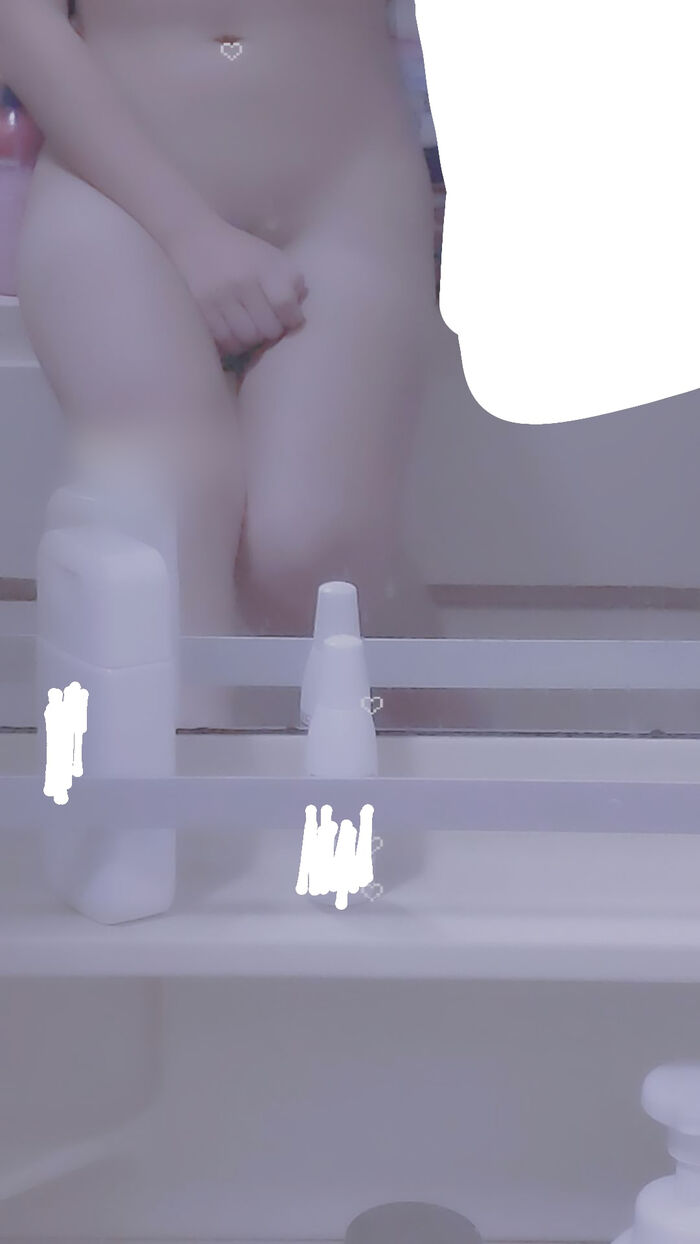 22-year-old female student holding a smartphone with her face and taking a naked hair nude mirror photo 23th image